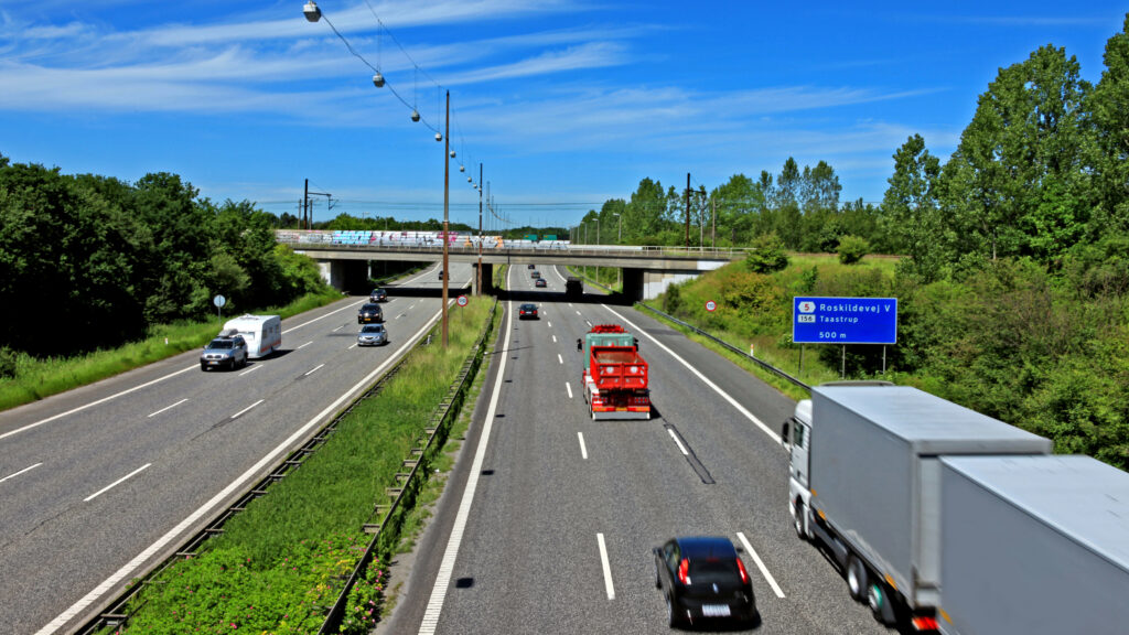 Motorvej med biler og grønne træer