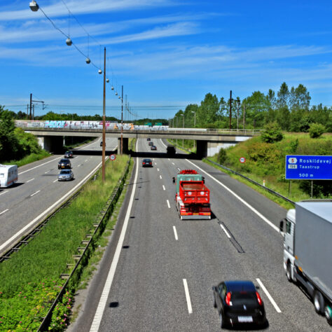 Motorvej med biler og grønne træer