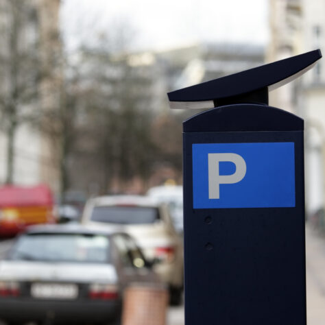 parkeringsskilt på gade med parkerede biler med træer uden blade ved siden af