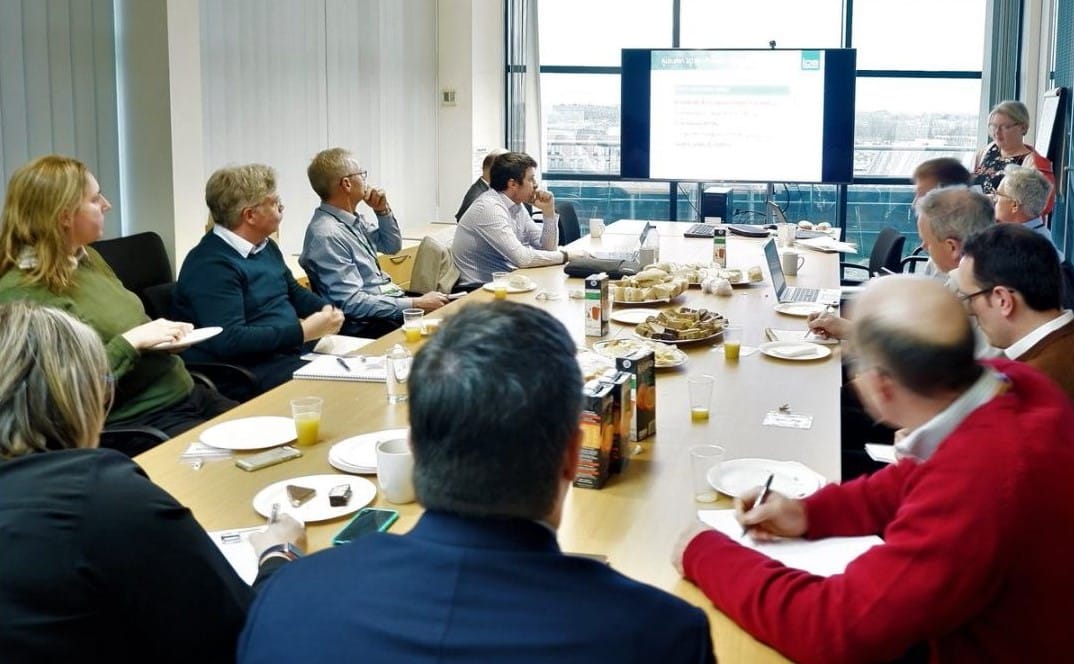 A group of colleagues sit in a board room for a meeting.