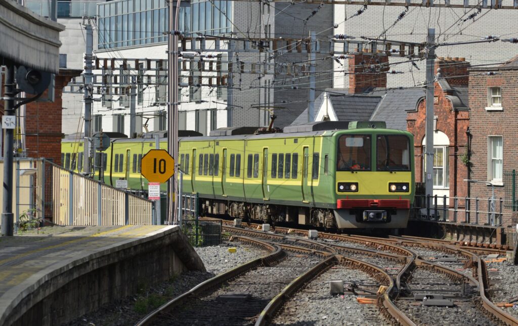 A green and yellow DART Dublin suburban train approaching a station in central Dublin