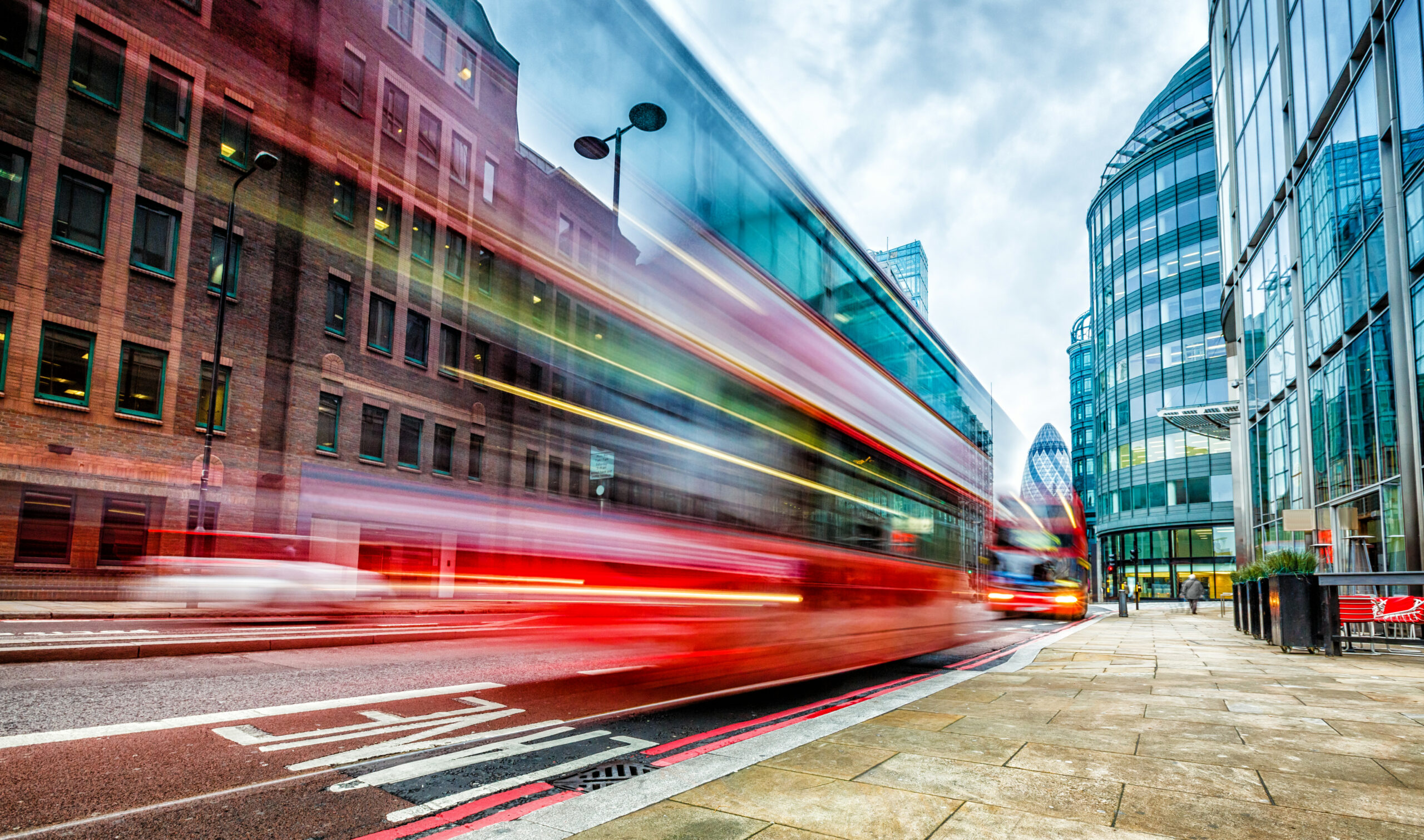 A bus blurred driving in London. The bus is red and is in the bus lane.