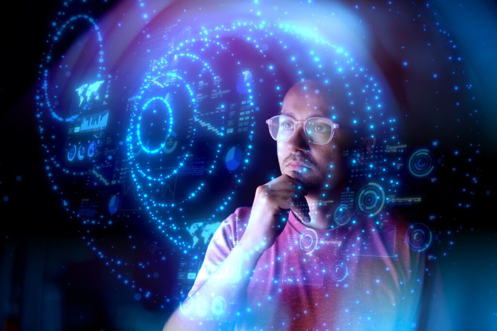 A man wearing glasses is looking at a dashboard of data. The man is wearing glasses and the data appears to be floating in front of him.
