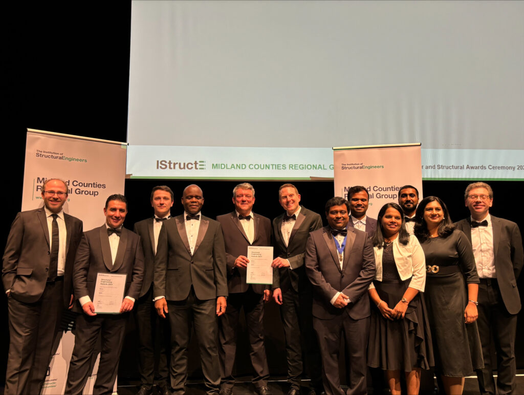 A photo of colleagues at the Institution of Structural Engineers' Midland Counties Structural Awards. They are all stood in a line wearing black tie style outfits. Two of them are holding the award certificates.