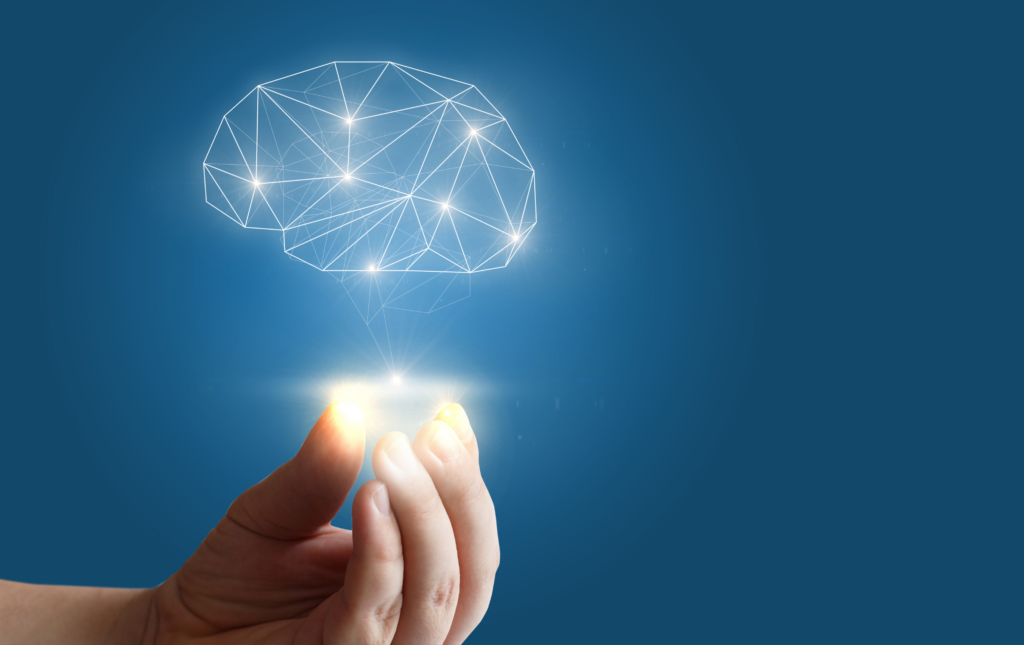 An outline drawing of a brain hovers above a hand. The brain is glowing and the hand is omitting light from its fingertips. The background of the image is blue.