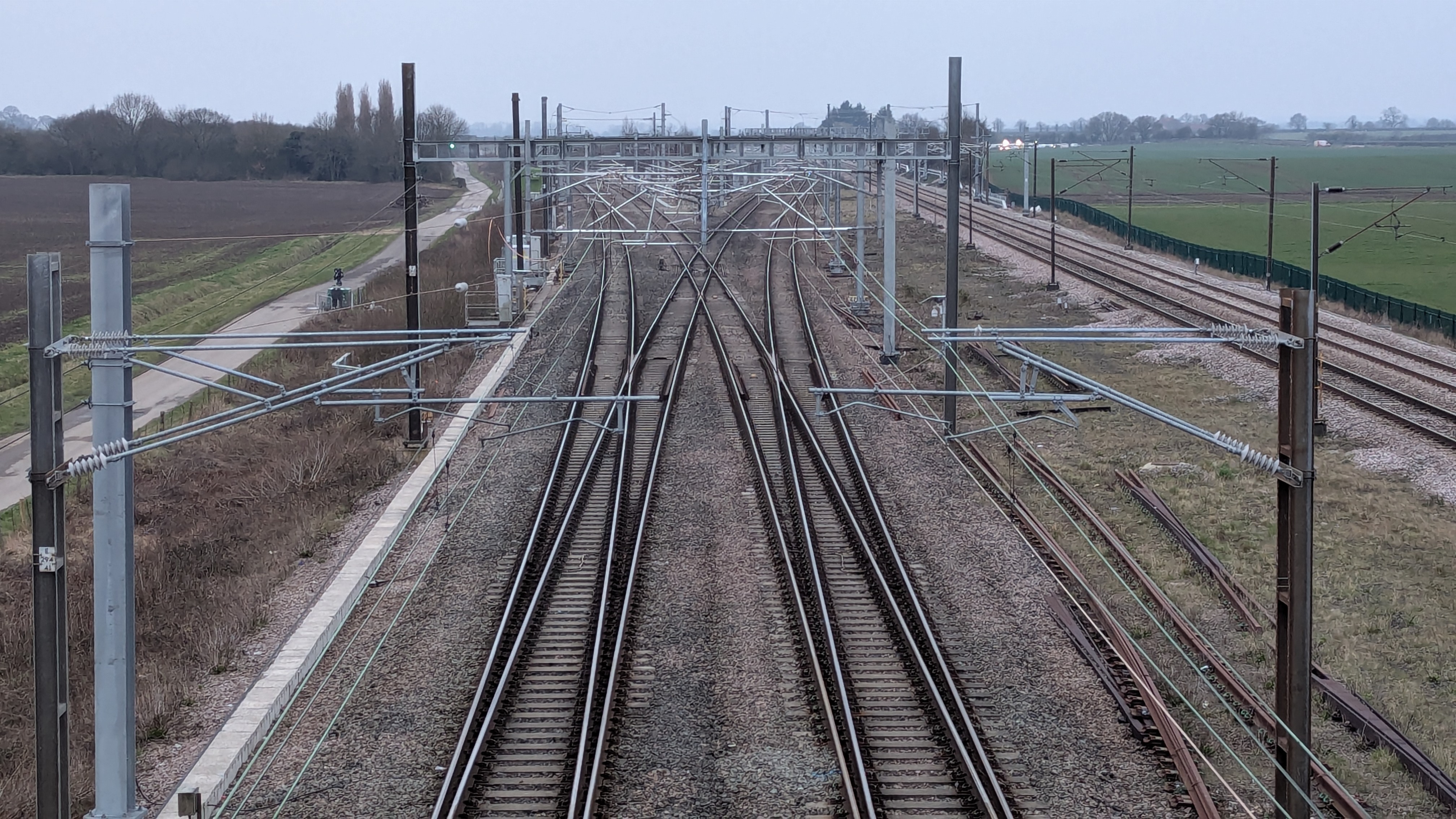 A photo of the TRU Colton Junction. The photo is taken from above the OLE wires and tracks as they stretch out into the distance.