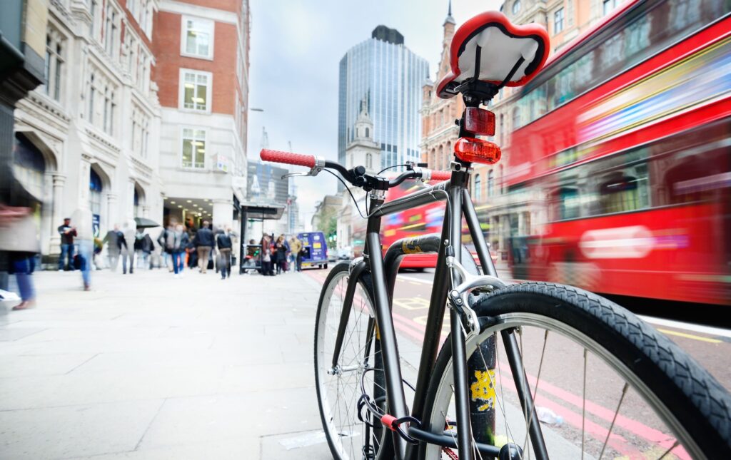 Bicycle parked on pavement with motion blur bus in the background