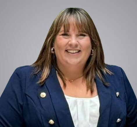 A headshot image of Jennifer Aston. Jennifer is wearing a white top, a navy blue suit jacket and is smiling at the camera.
