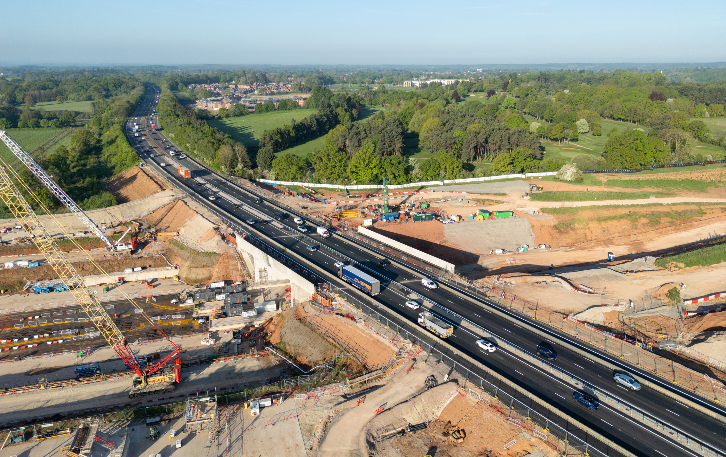 HS2 construction site at the A46 Kenilworth bypass. The photo shows the highway reopened for traffic. In the background are lots of trees and fields.