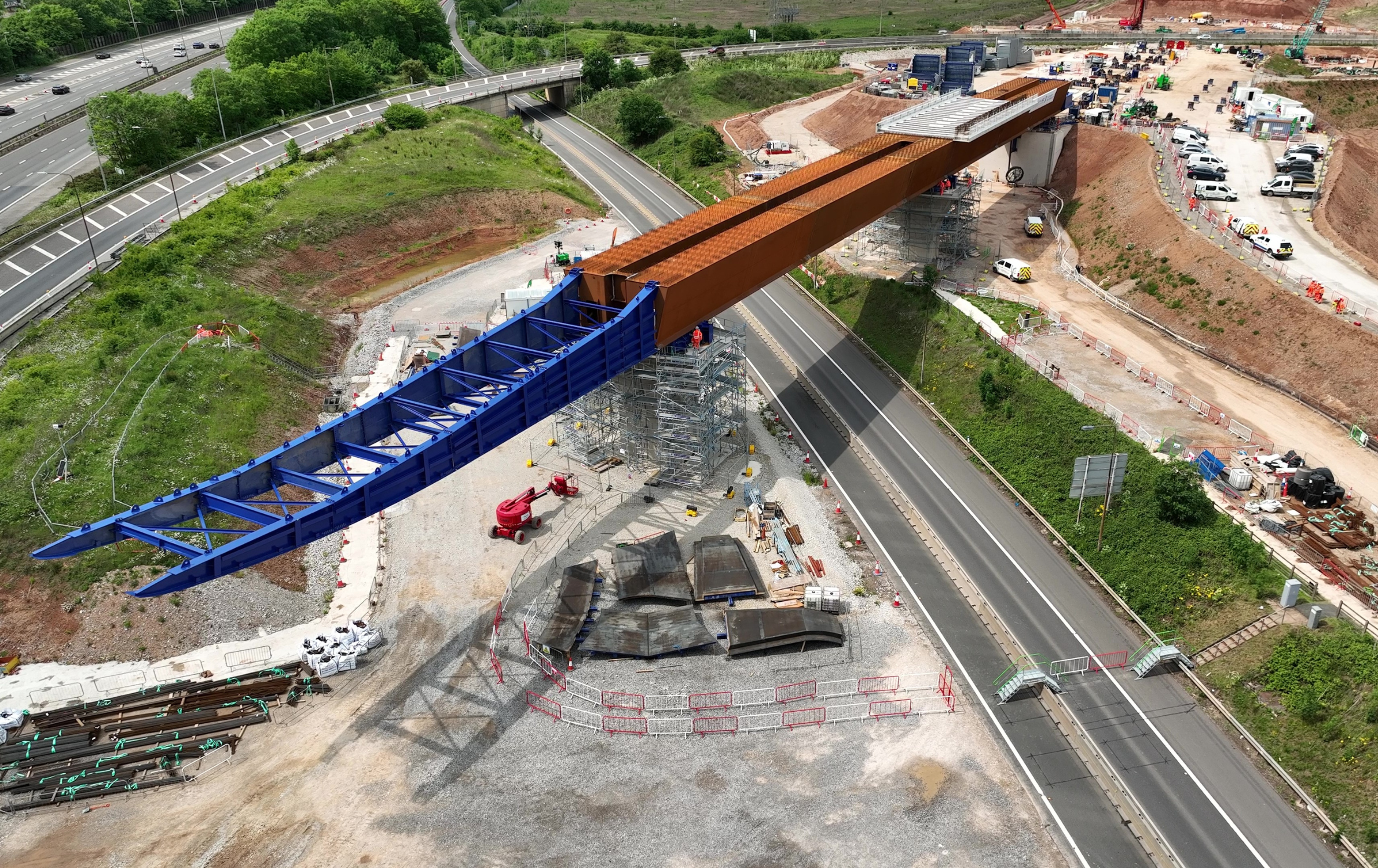 A birds eye view photo of the first section of the M6 South viaduct sliding into position on the HS2 project. The structure is pictured spanning across a road and is surrounded by the construction site on either side.
